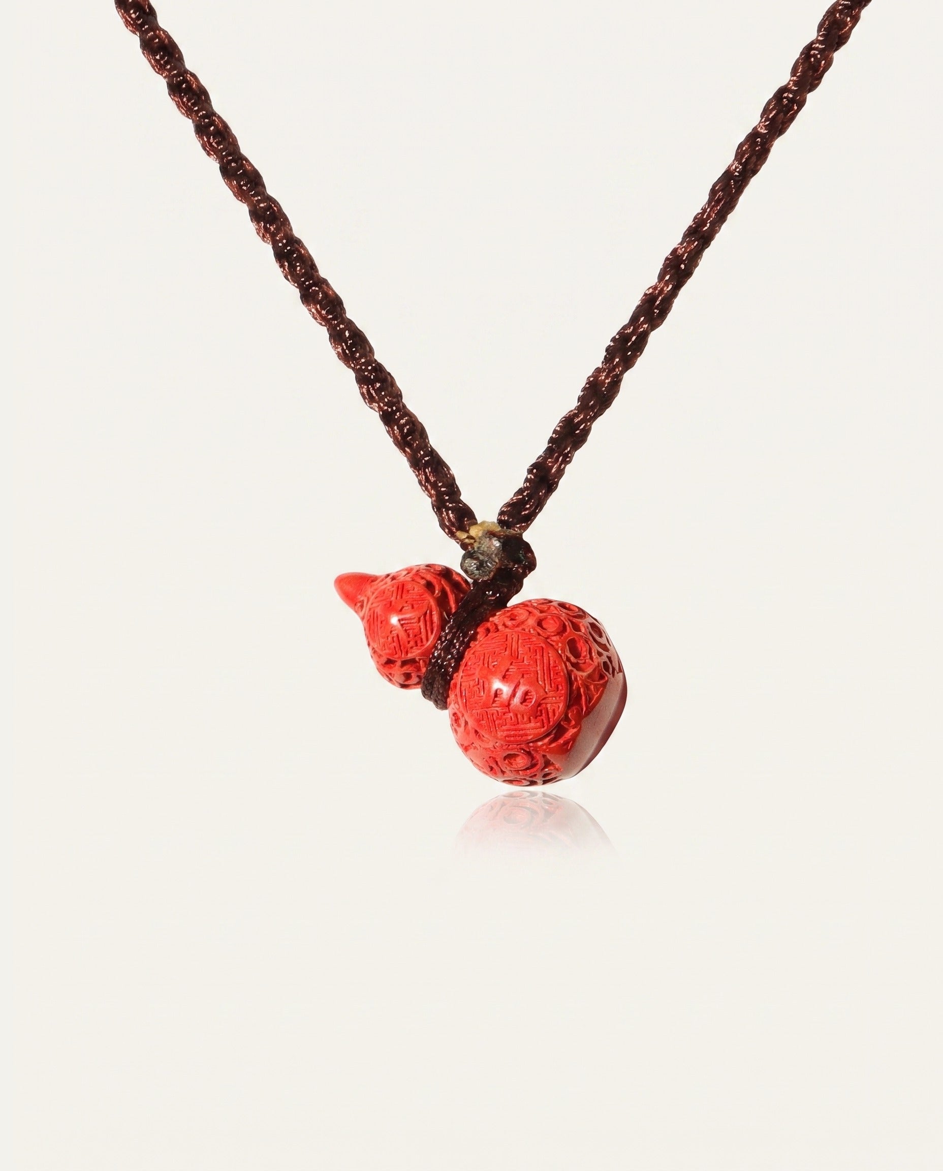 Carved Hulu cinnabar necklace on ivory studio background