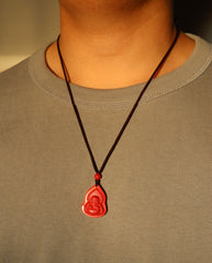Seated Laughing Buddha cinnabar necklace on dark background