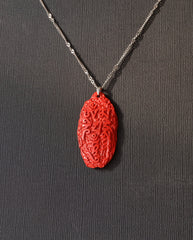 Six Character Mantra cinnabar necklace on dark background