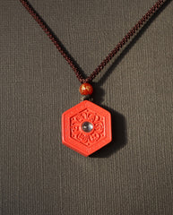 Six Character Mantra Hexagon cinnabar necklace on dark background