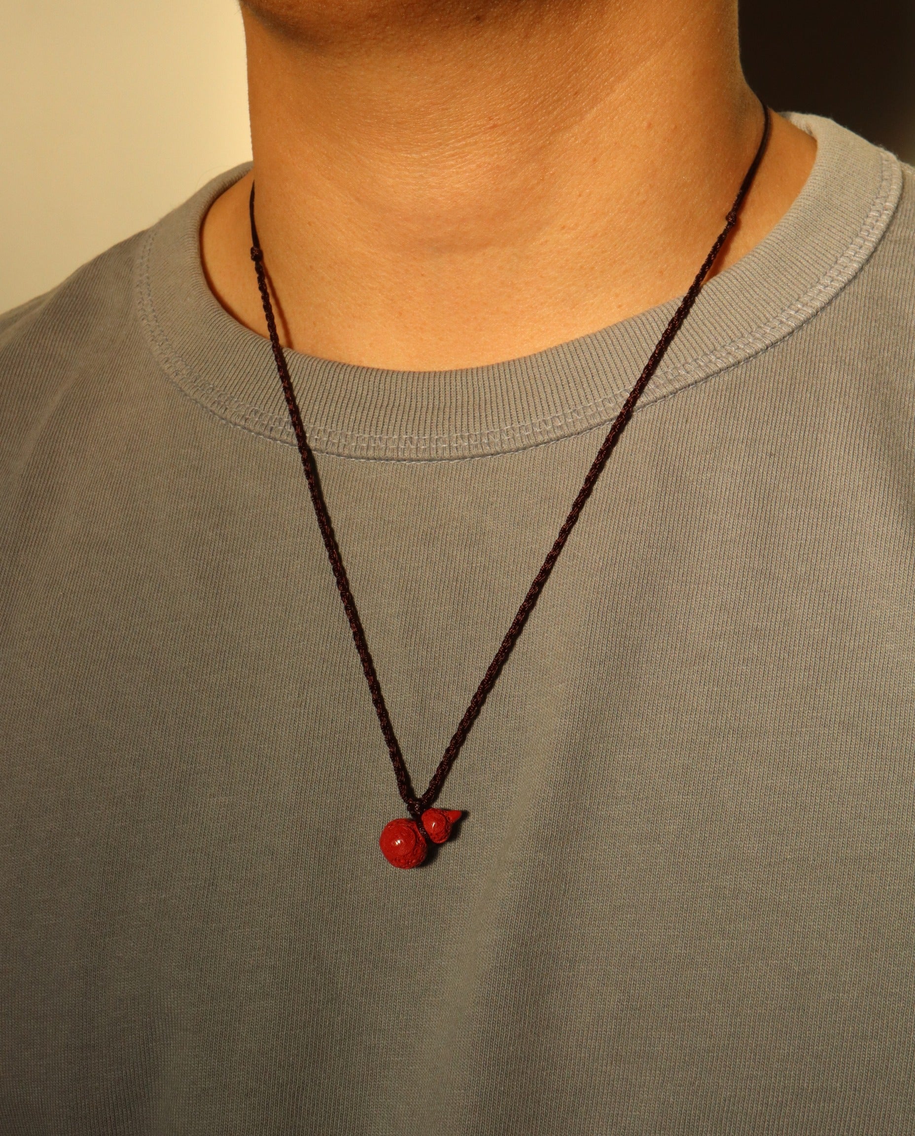 Carved Hulu cinnabar necklace on dark background