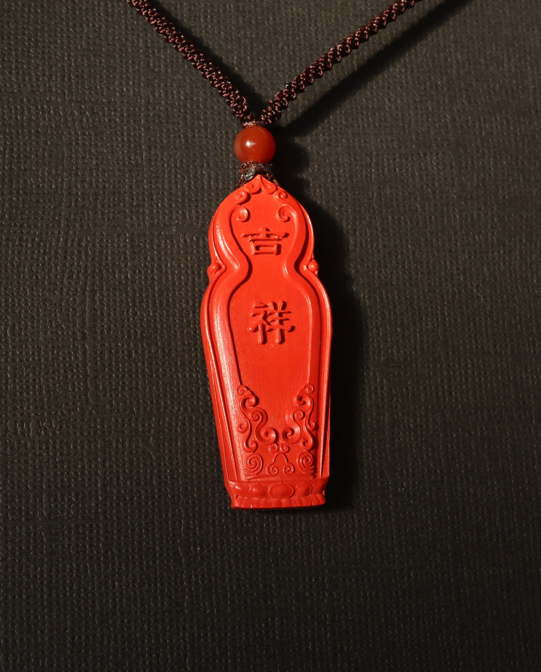Guan Yin cinnabar necklace on dark background