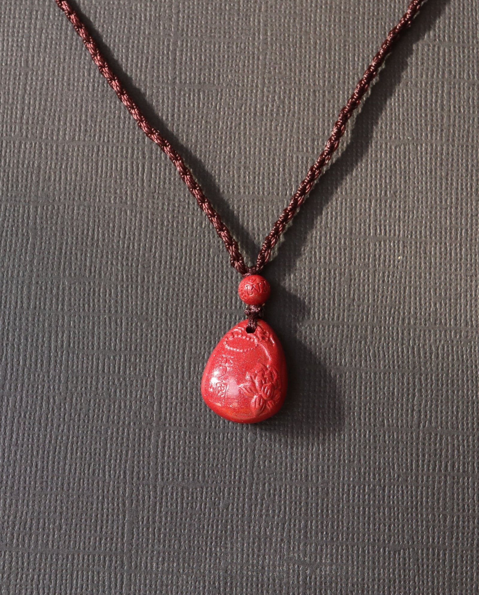 Heart Sutra Teardrop cinnabar necklace on dark background