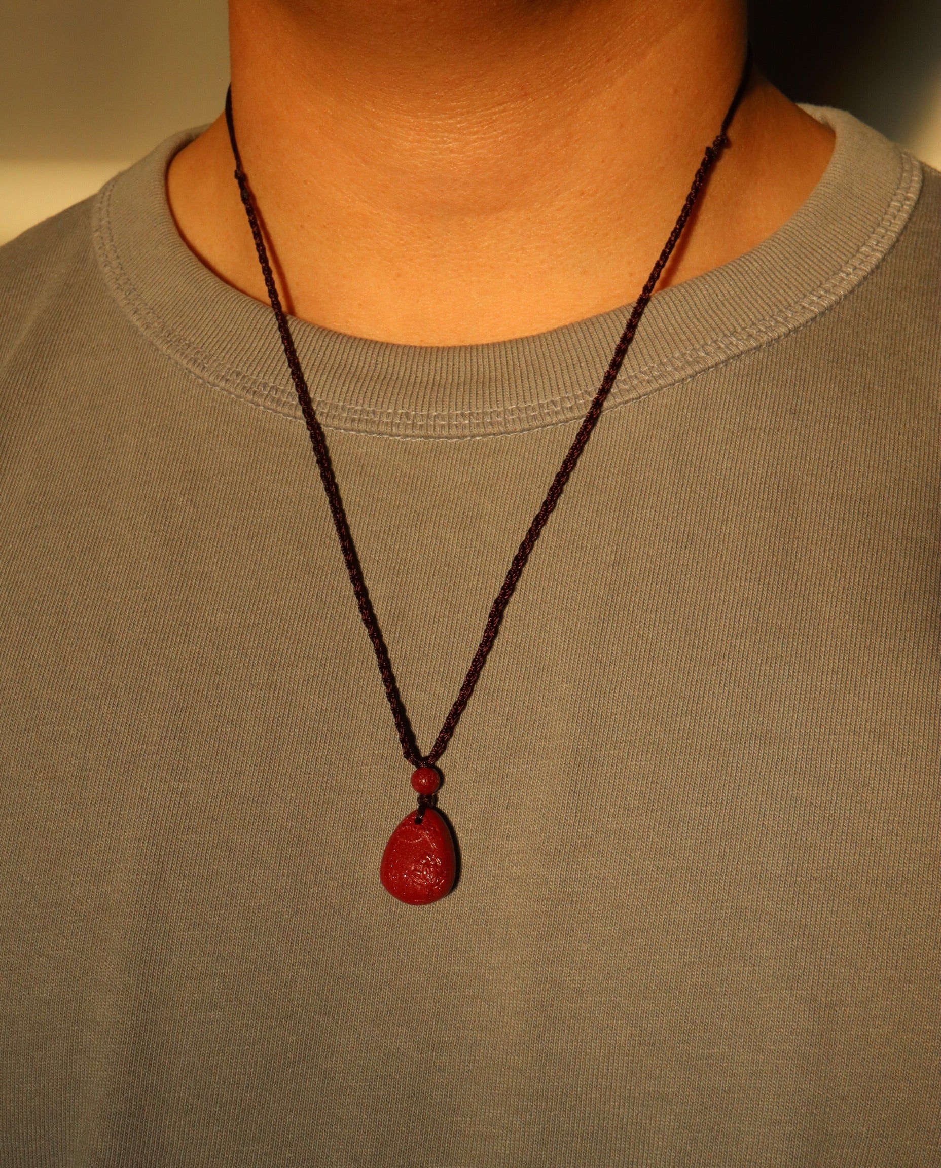 Heart Sutra Teardrop cinnabar necklace on dark background
