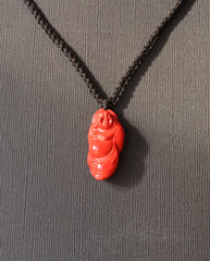 Laughing Buddha cinnabar necklace on dark background