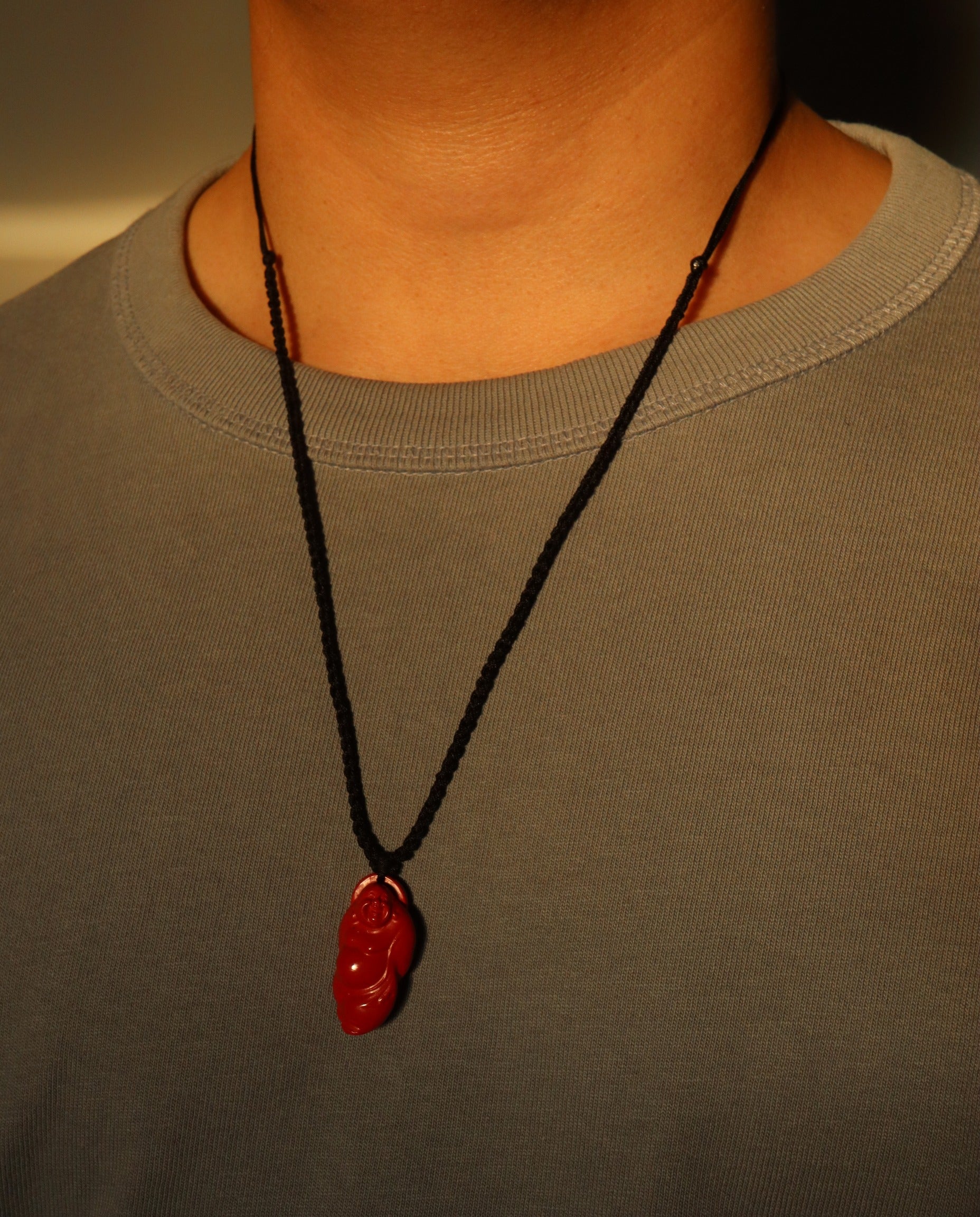 Laughing Buddha cinnabar necklace on dark background