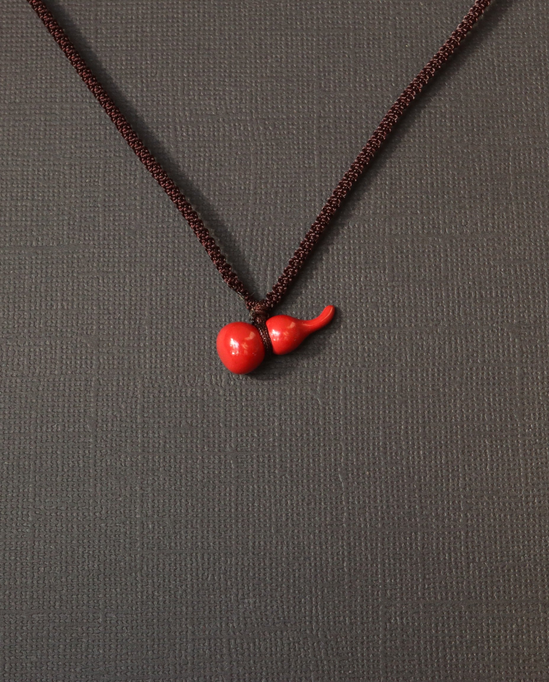 Mini Hulu cinnabar necklace on dark background