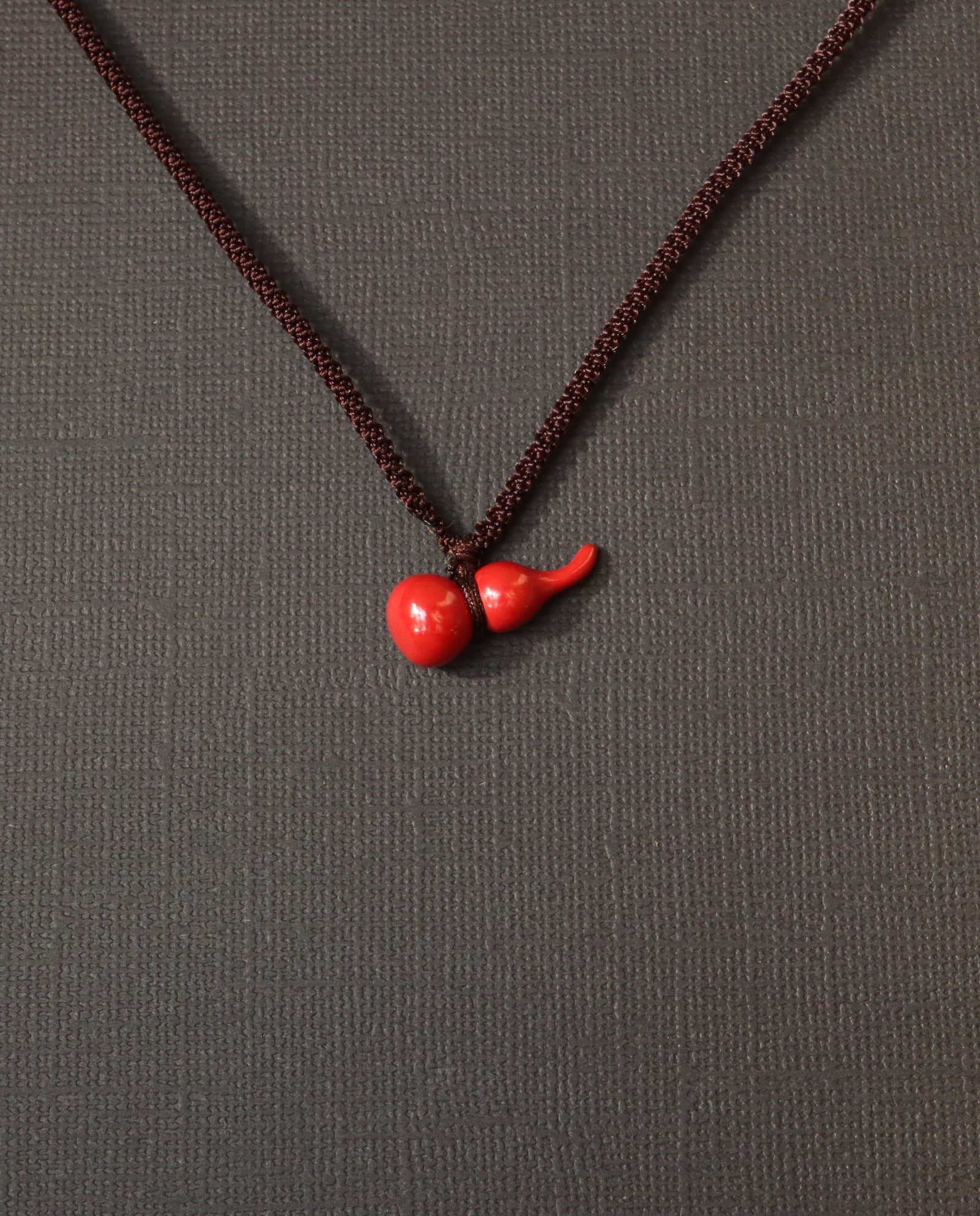 Mini Hulu cinnabar necklace on dark background
