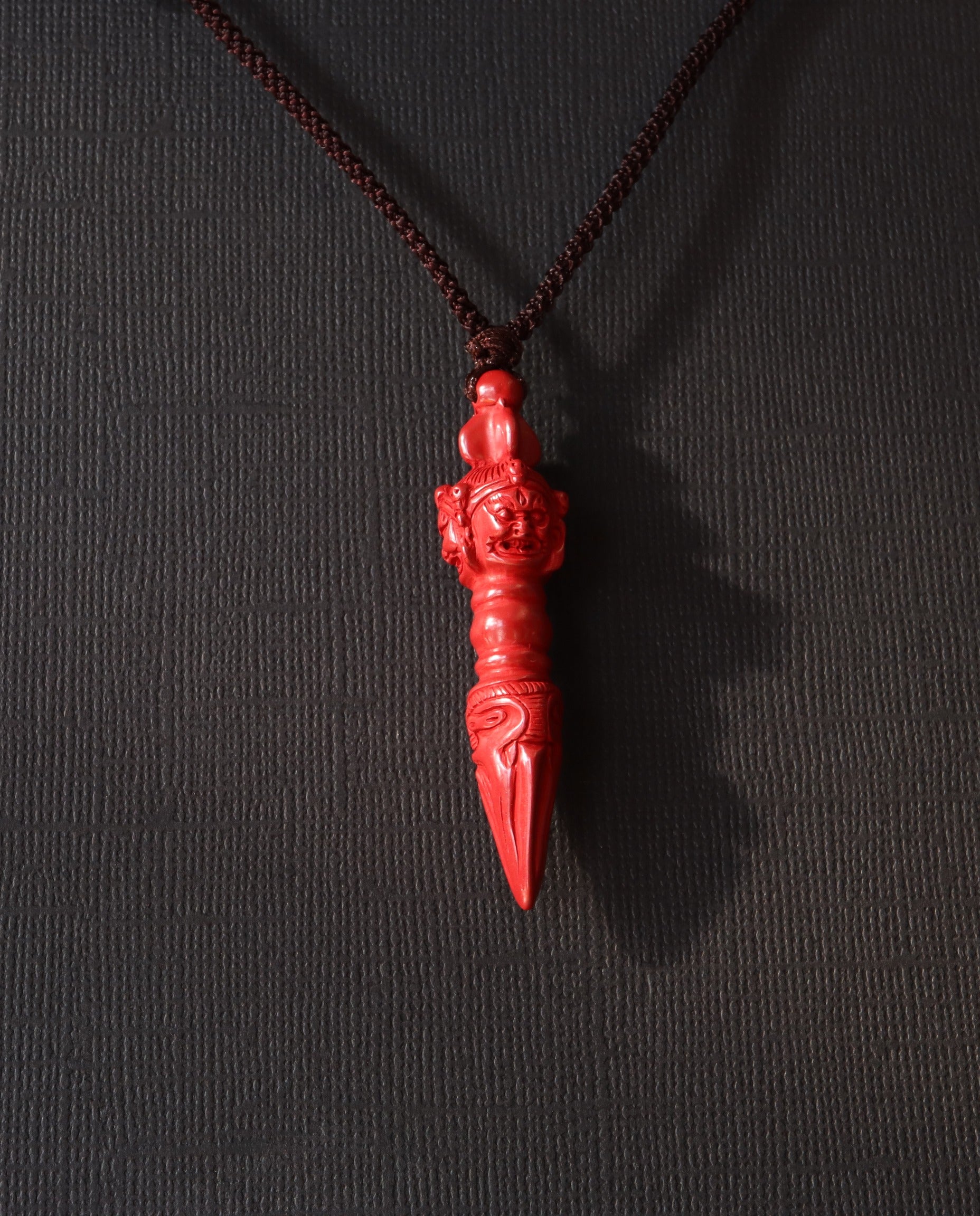 Phurba cinnabar necklace on dark background