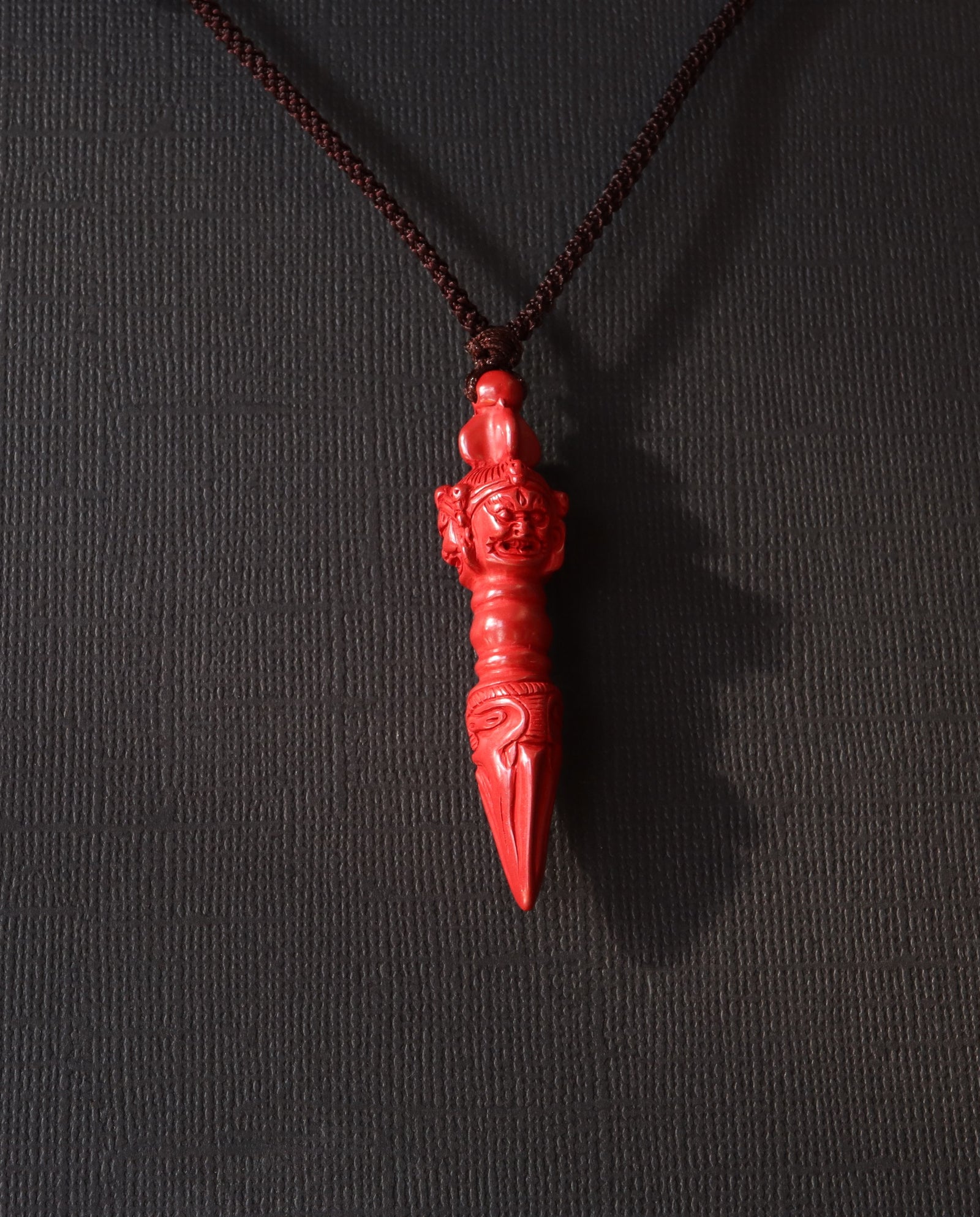 Phurba cinnabar necklace on dark background