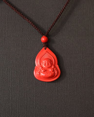 Seated Laughing Buddha cinnabar necklace on dark background