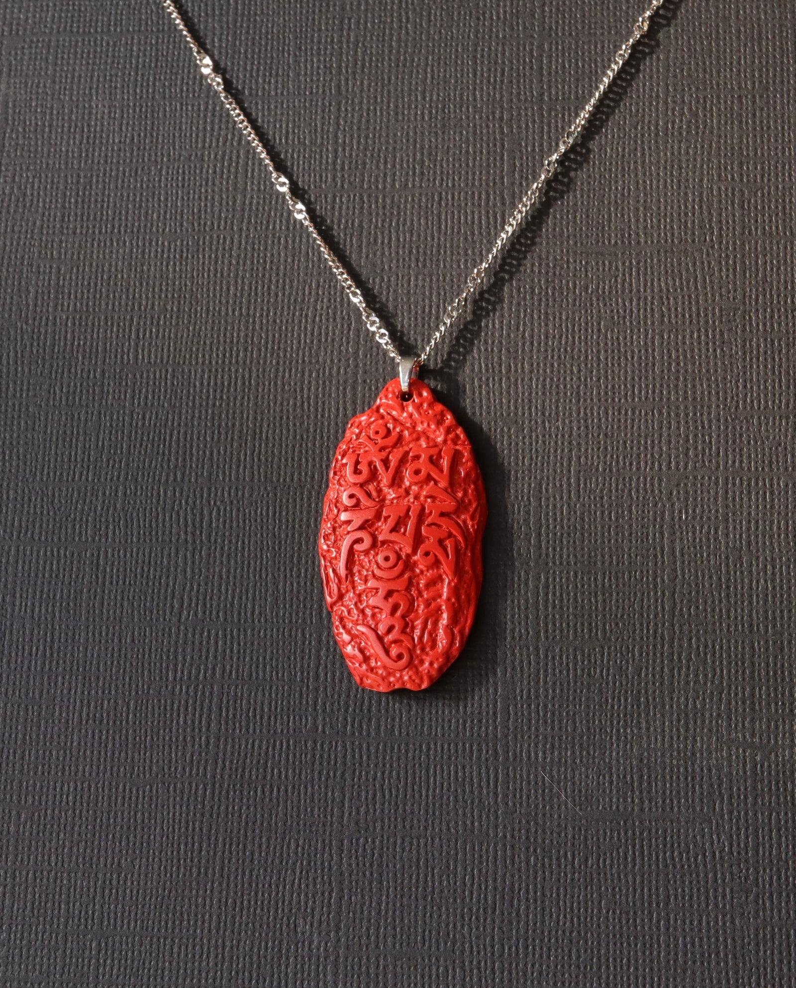 Six Character Mantra cinnabar necklace on dark background