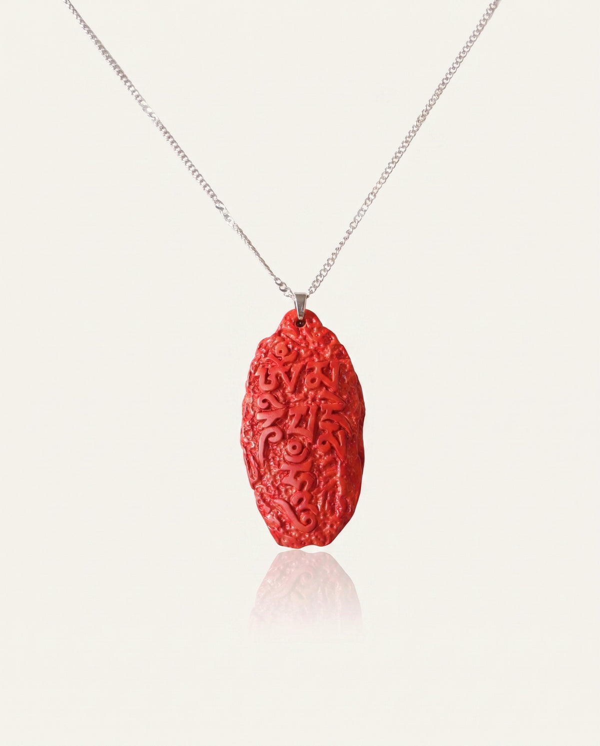 Six Character Mantra cinnabar necklace on ivory studio background