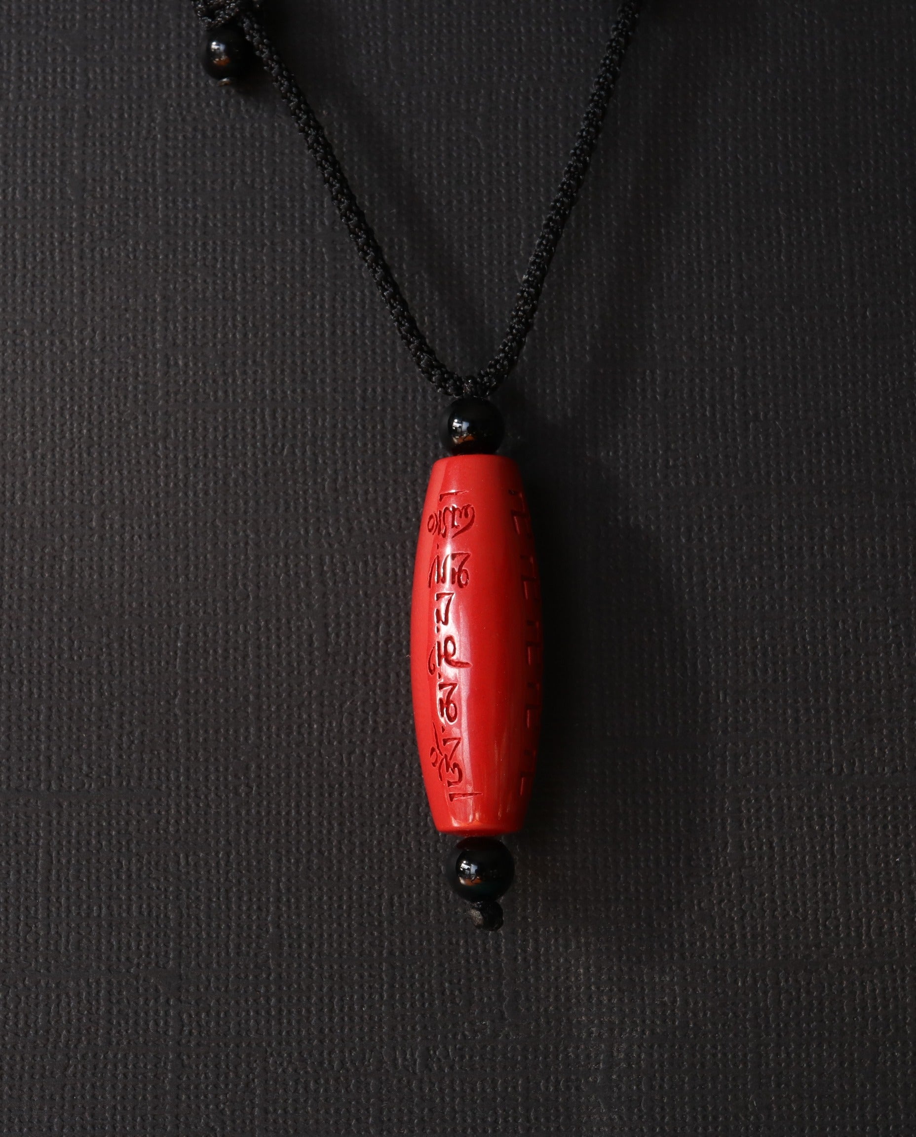 Six Character Mantra Cylinder cinnabar necklace on dark background