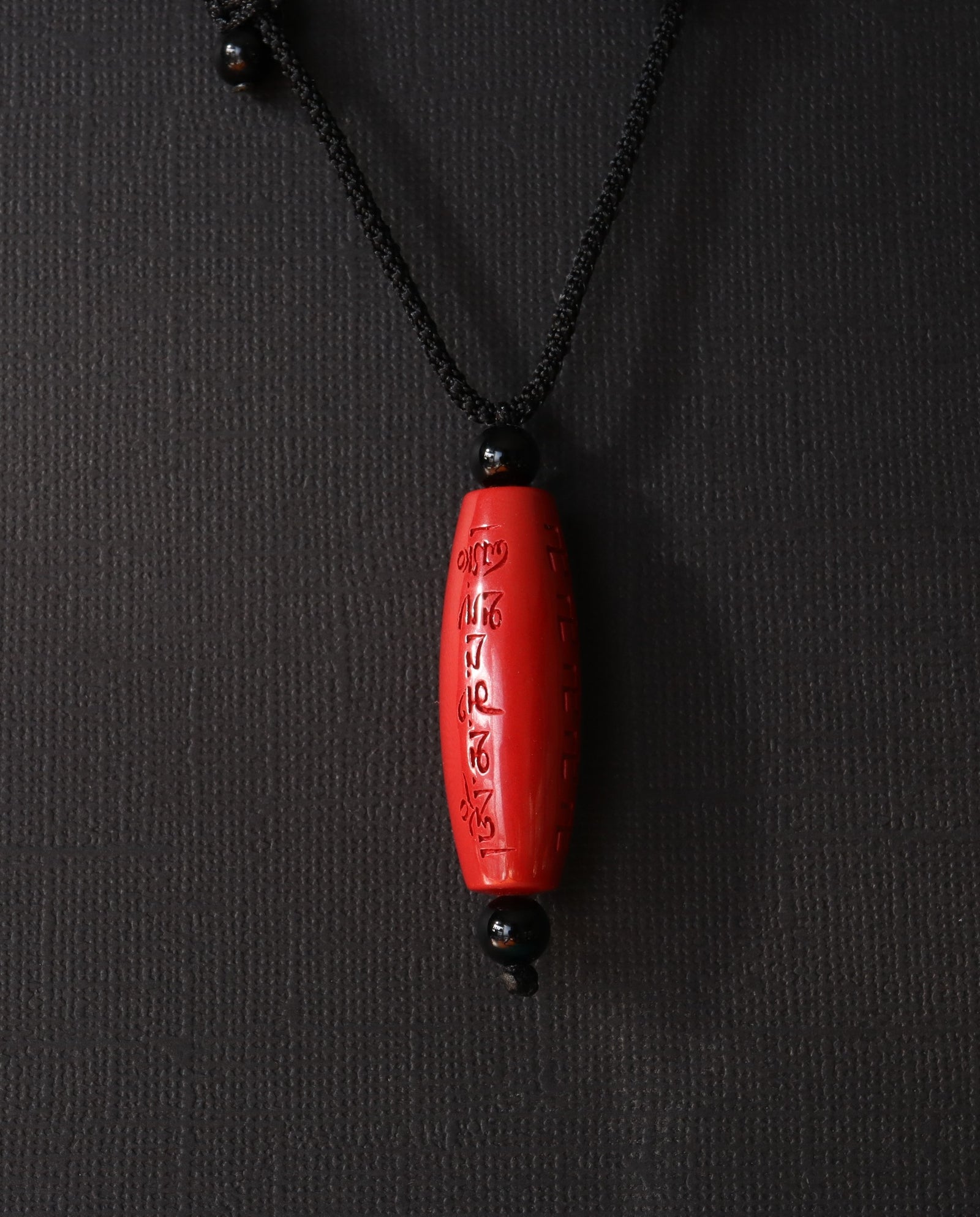 Six Character Mantra Cylinder cinnabar necklace on dark background