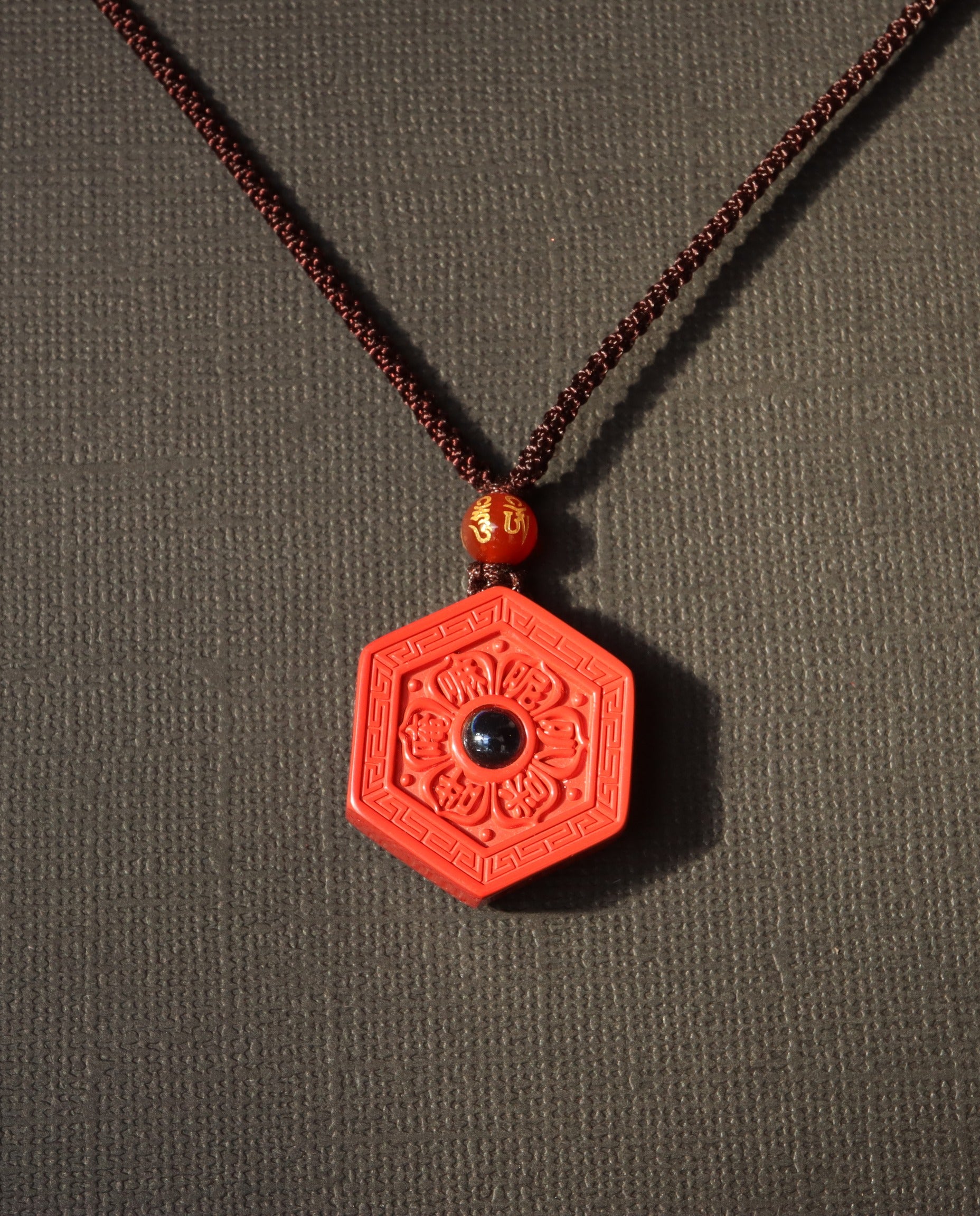 Six Character Mantra Hexagon cinnabar necklace on dark background