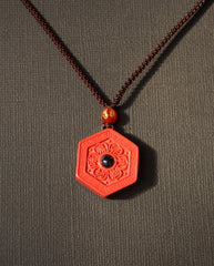 Six Character Mantra Hexagon cinnabar necklace on dark background