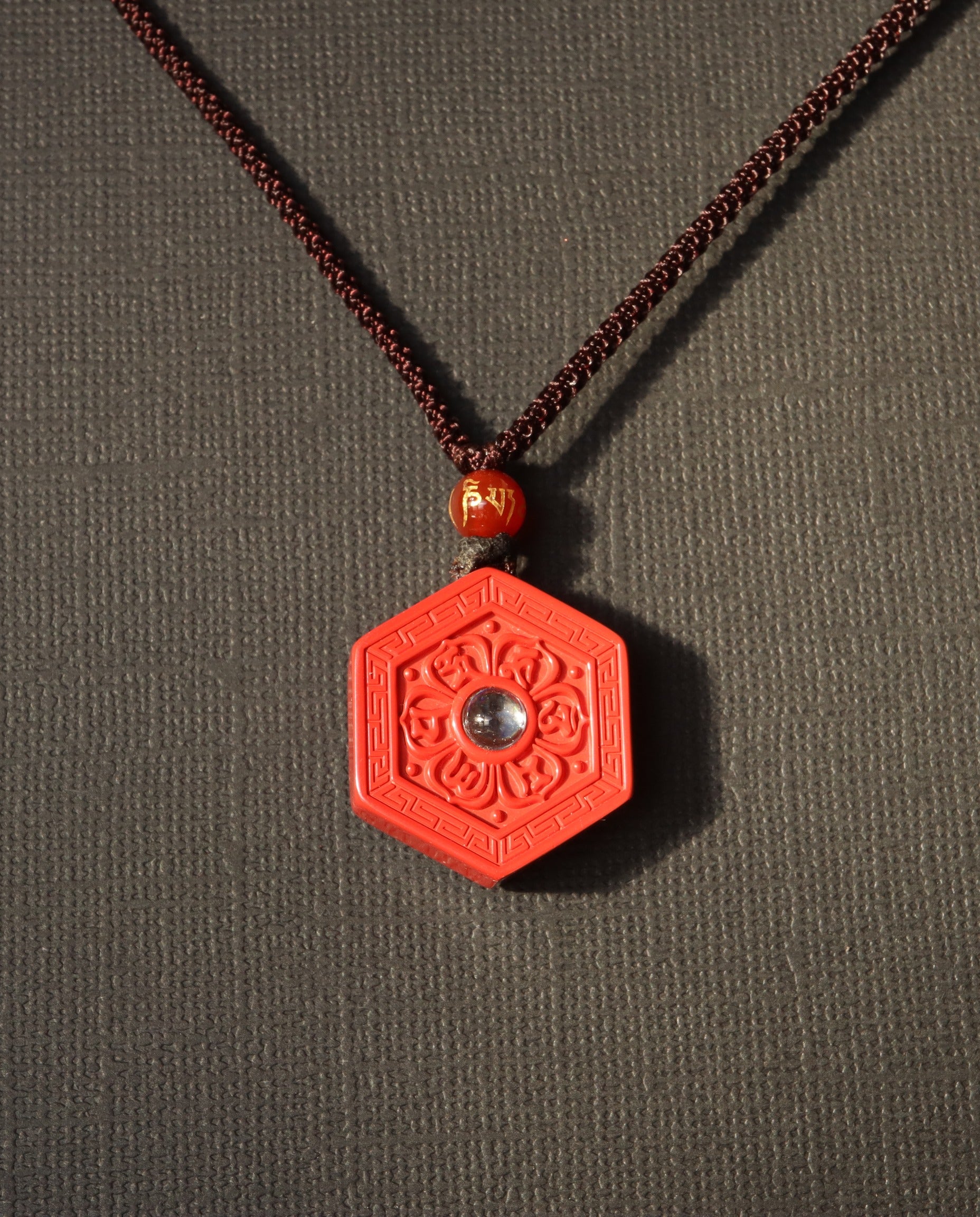 Six Character Mantra Hexagon cinnabar necklace on dark background