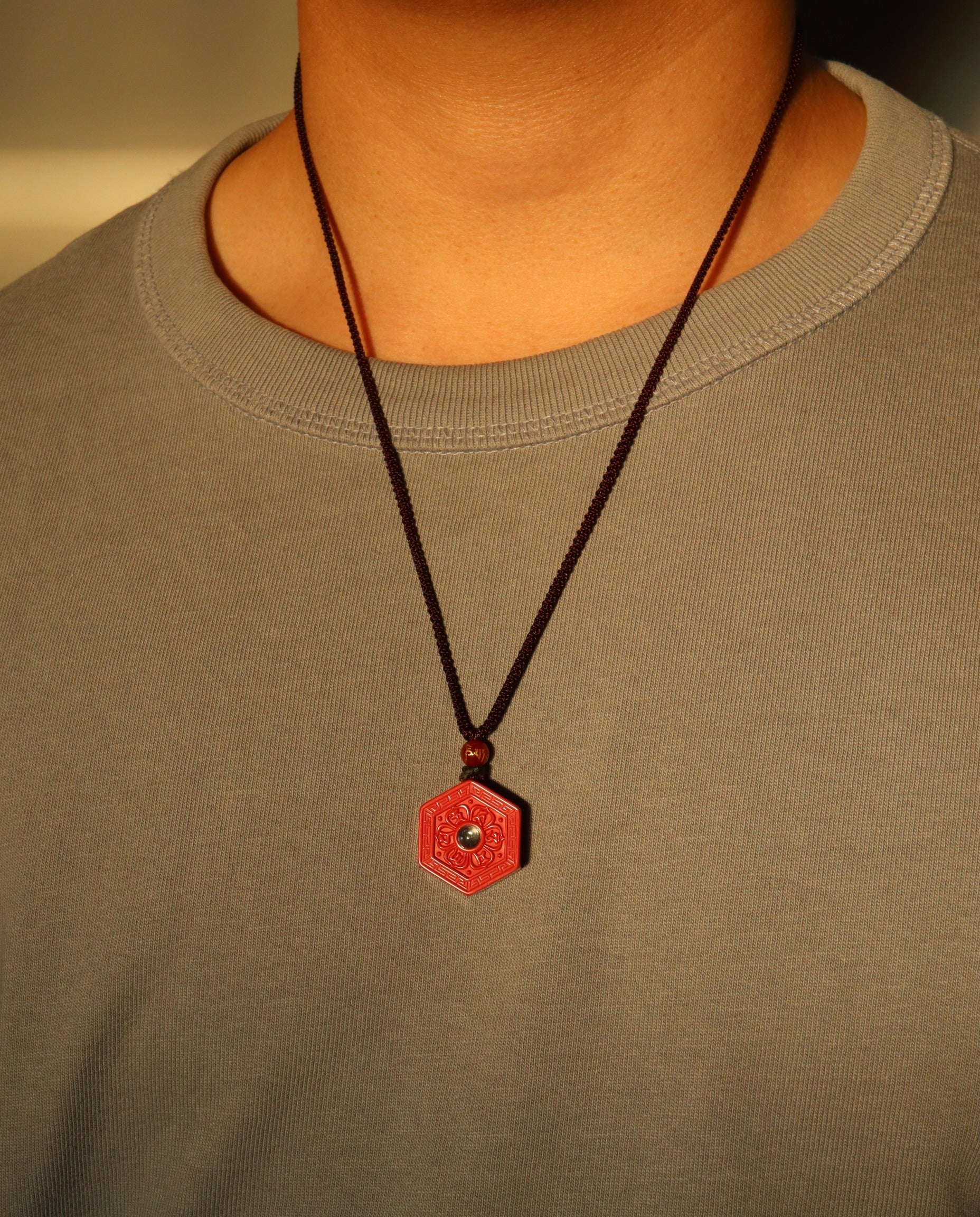 Six Character Mantra Hexagon cinnabar necklace on dark background