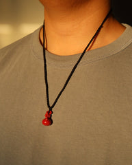 Smooth Hulu cinnabar necklace on dark background