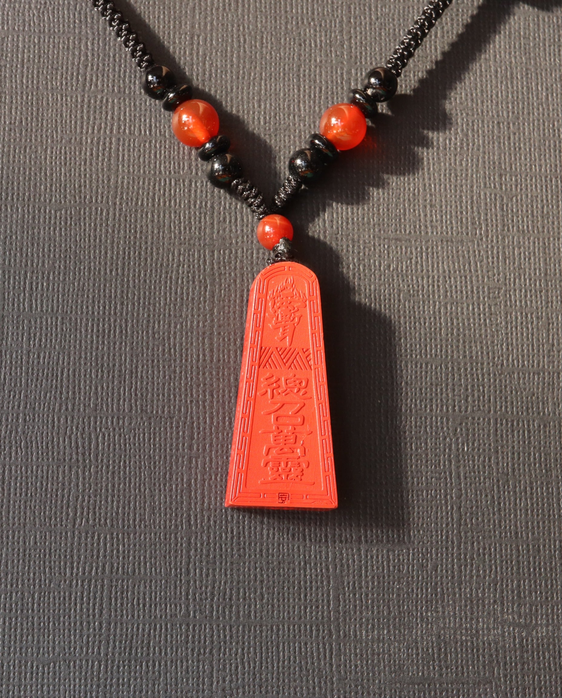 Wealth Talisman Trapezoid cinnabar necklace on dark background