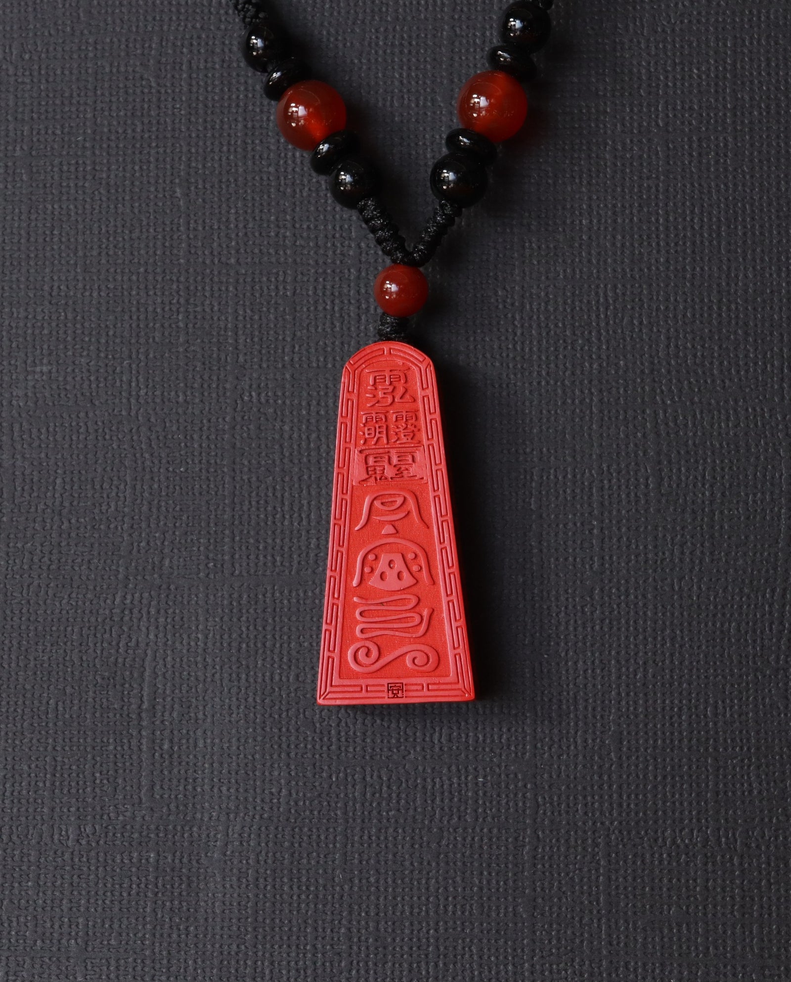 Wealth Talisman Trapezoid cinnabar necklace on dark background